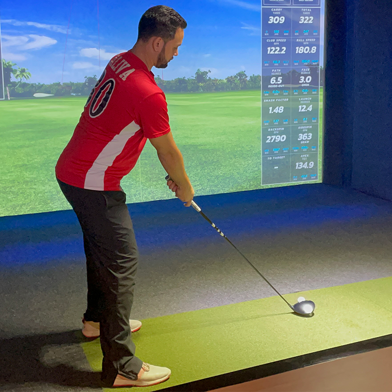 golfer tee-ing up at golf simulator